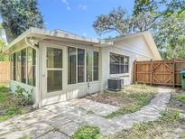 A home's cozy backyard with a patio, screened enclosure, and wooden fence under a clear, blue sky at 809 Sugar House Blvd, Port Orange, FL 32129