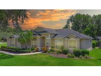 Inviting single-story home with lush landscaping, mature trees, and manicured lawn under a beautiful sunset sky at 875 Bentley Green Cir, Winter Springs, FL 32708