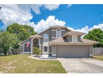 Charming two-story home featuring arched windows, a well-maintained lawn, and an inviting walkway at 1061 Providence Ln, Oviedo, FL 32765