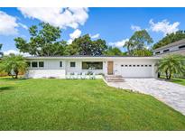 Charming home with a well-manicured lawn, complemented by a brick paver driveway and mature trees at 2102 Ivanhoe Rd, Orlando, FL 32804