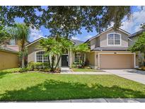 Charming two-story home featuring a lush green lawn and mature tropical landscaping at 2451 Ridgemoor Dr, Orlando, FL 32828
