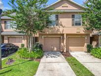 Inviting townhouse featuring a well-manicured lawn, attached garage, and neutral-toned exterior at 3599 Caruso Pl, Oviedo, FL 32765