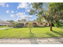 Charming single-story home with arched entryway and a well-maintained lawn on a sunny day at 5527 Sandalwood Dr, Orlando, FL 32839