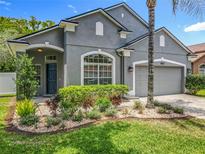 Charming gray stucco home with well-manicured landscaping and a large, arched window at 5852 Stafford Springs Trl, Orlando, FL 32829