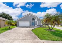 Charming single Gathering home featuring a blue door, landscaped front yard and a two car garage at 603 Cypress Tree Ct, Orlando, FL 32825