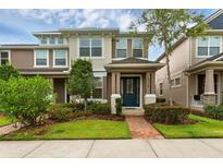 Inviting two-story townhome featuring a well-manicured lawn, beautiful landscaping, and a charming blue front door at 8968 Hildreth Ave, Orlando, FL 32832