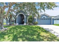 Charming single-story home featuring a manicured lawn, arched entryway and an attached two-car garage at 1031 Seneca Trl, St Cloud, FL 34772