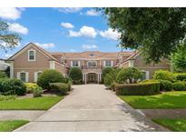 Inviting, two-story house with a red tile roof, manicured shrubs and a brick driveway at 10915 Emerald Chase Dr, Orlando, FL 32836