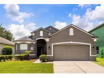 Beautiful exterior shot of a gray house with well-manicured landscaping and a two-car garage at 13658 Hidden Forest Cir, Orlando, FL 32828
