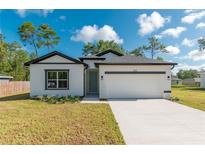 Beautiful white house with black accents, a two-car garage, and a well-maintained lawn at 6291 Sw 133Rd Street Road, Ocala, FL 34473