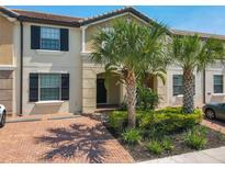 Inviting townhome featuring a red brick driveway, lush landscaping, and classic architectural details at 8911 Geneve Ct, Kissimmee, FL 34747