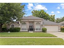 Charming single-story home with arched windows, lush lawn, mature trees, and a welcoming double-door entrance at 1103 Lake Legro Ct, Orlando, FL 32835
