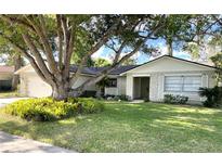 Charming single-story home featuring a stone facade, lush lawn, and a mature shade tree at 139 Stoney Ridge Dr, Longwood, FL 32750