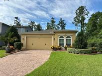 Charming single-story home with a brick driveway, well-manicured lawn, and lush landscaping at 1573 Amber Leaf Cir, Ocoee, FL 34761