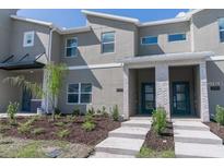 Modern townhome featuring a gray facade with a landscaped front yard and decorative stone accents around the entryway at 2460 Reading Trl, Kissimmee, FL 34746