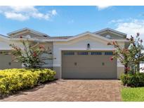 Beuatiful two-car garage with a brick driveway and flowering plants in front of the building at 2571 Yellow Brick Rd, St Cloud, FL 34772