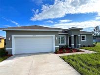 Charming single-story home featuring a two-car garage, gray stucco, manicured landscaping, and a concrete driveway at 2579 Sw 146Th St, Ocala, FL 34473