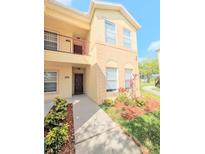 Two-story condo with a private balcony and a well-manicured lawn with shrubs and mulched flower beds at 2816 Club Cortile Cir # A, Kissimmee, FL 34746
