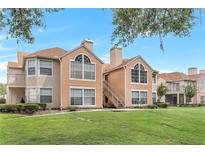 Condo exterior featuring well-manicured lawn, beige siding, and a staircase leading to the upper levels at 698 Roaring Dr # 382, Altamonte Springs, FL 32714