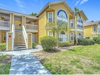 Street-level exterior of a two-story yellow townhome, featuring large windows and landscaping at 8722 Rockingham Ter # B, Kissimmee, FL 34747