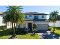 Charming two-story home featuring a two-car garage, lush landscaping, and a welcoming front entrance with elegant columns at 10427 Royal Cypress Way, Orlando, FL 32836