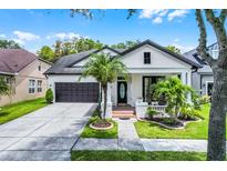 Charming home featuring a manicured lawn, beautiful landscaping, a two-car garage, and a welcoming front porch at 14213 Southern Red Maple Dr, Orlando, FL 32828