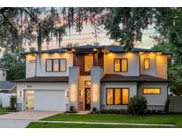 Striking two-story home with ambient outdoor lighting, complemented by a brick driveway and a well-manicured front lawn at 1620 S Eola Dr, Orlando, FL 32806