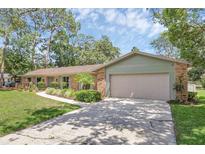 Charming one-story brick home with well-manicured lawn, mature trees, and a two-car garage at 223 Royal Oaks Cir, Longwood, FL 32779