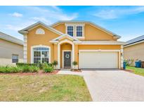 Charming two-story home featuring a well-manicured lawn, brick driveway, and attached two-car garage at 233 Cadiz Loop, Davenport, FL 33837