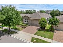Well-maintained home featuring a stone facade, brick driveway, manicured lawn, and an attached two-car garage at 2829 Red Alder Blvd, Ocoee, FL 34761
