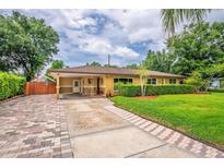 Charming single-story home featuring a manicured lawn, brick driveway, and a welcoming covered entryway at 6430 Yellowstone St, Orlando, FL 32807