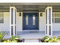Charming front entrance featuring a blue double door, white brick, and modern light fixtures at 102 Linda Ln, Lake Mary, FL 32746