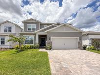 Charming two-story home features a brick driveway, manicured lawn, and welcoming covered porch at 13617 Haulover Beach Ln, Orlando, FL 32827