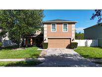 Two-story home featuring a two-car garage, well-manicured lawn, and mature tree at 14308 Abington Heights Dr, Orlando, FL 32828