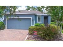 Charming single-story home with a brick driveway, lush landscaping, and a welcoming blue exterior at 1529 Chelsea Manor Cir, Deland, FL 32724