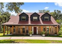 Charming brick home featuring a covered porch with exposed beams and dormer windows at 1815 Big Oak Ln, Kissimmee, FL 34746