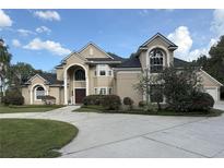 Stately tan home boasting an elegant entrance, arched windows, and lush landscaping at 1865 S Tanner Ct, Deltona, FL 32738