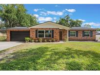 Charming brick home featuring a well-manicured lawn and attached garage at 209 Carriage Hill Dr, Casselberry, FL 32707