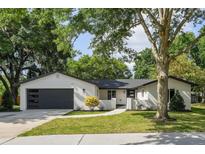 Beautifully landscaped single-story home with a modern garage and mature trees at 213 W Tilden St, Winter Garden, FL 34787