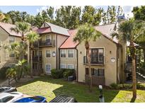 Multi-level condo building with red roofs, black metal balconies, mature landscaping, and palm trees at 236 Afton Sq # 109, Altamonte Springs, FL 32714