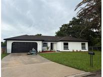Charming single-story home with a well-maintained lawn, freshly painted, and a black garage door at 3 Spur Ct, Kissimmee, FL 34743