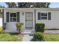 Charming home featuring a secure metal screen door and neatly trimmed bushes flanking the entrance at 306 Modest St, Lakeland, FL 33805