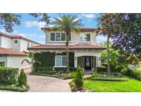 Stunning two-story home with a tile roof, beautiful landscaping, and an inviting brick walkway leading to the front door at 800 Hamilton Place Ct, Winter Park, FL 32789