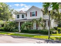 Charming two-story home with lush landscaping, red shutters, and a welcoming front porch with columns at 8113 Key West Dove St, Winter Garden, FL 34787