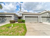 Townhouse exterior features a multi-car garage, neutral paint, manicured shrubs and green grass at 1128 Travertine Ter, Sanford, FL 32771