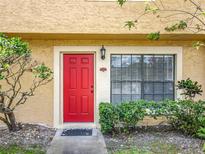 Charming home featuring a vibrant red front door, complemented by lush landscaping and a window at 3247 Forest Oaks Ct # 116, Winter Park, FL 32792