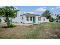 Charming single-story home with a well-maintained lawn, white fence and a blue front door at 4420 Lake Lawne Ave, Orlando, FL 32808