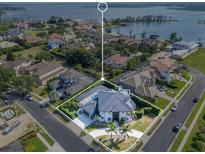 Aerial view of a luxury home with a blue roof, circular driveway, and stunning lake views at 5708 Emerington Cres, Orlando, FL 32819