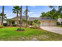 Charming single-story home featuring a three-car garage, lush landscaping, and mature palm trees at 7237 Woodville Cres, Orlando, FL 32819