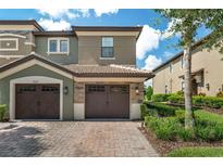 Two-story townhome featuring a tile roof, brick paver driveway, and a two-car garage at 8970 Azalea Sands Ln # 2302, Davenport, FL 33896